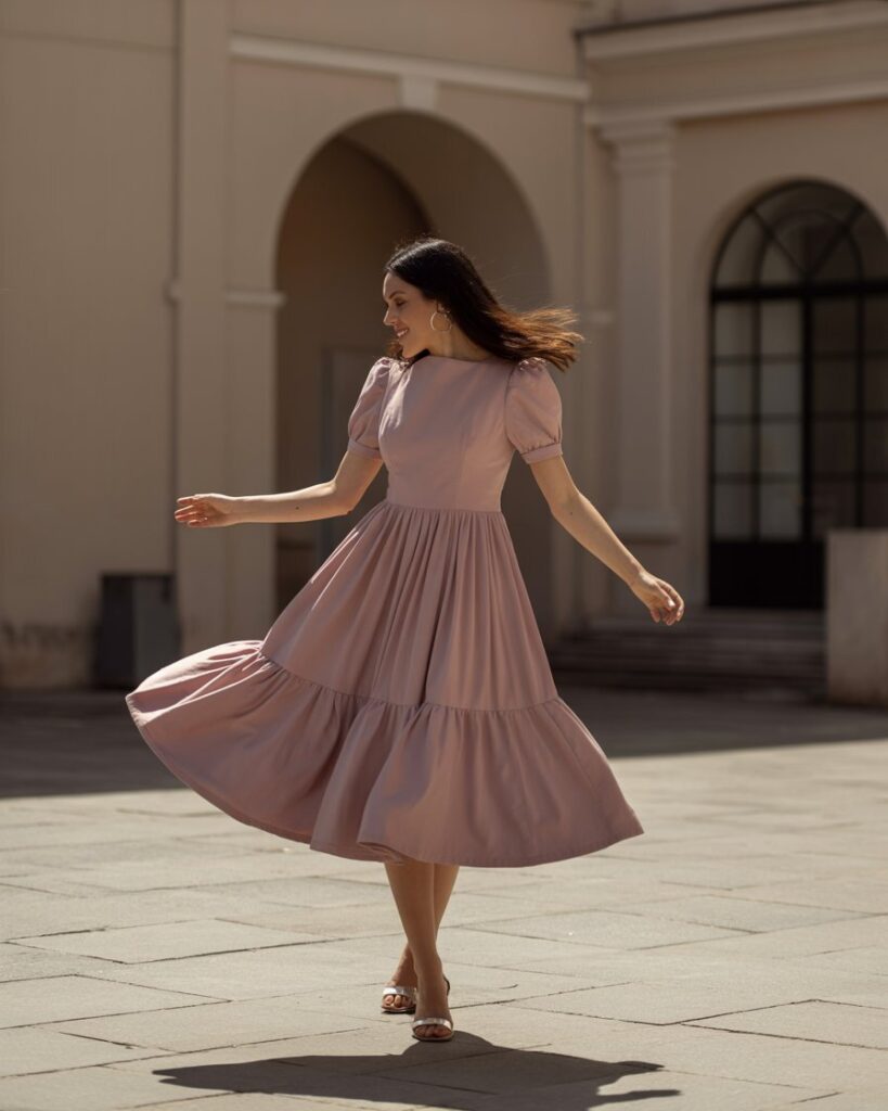 Woman in a structured pastel midi dress twirling in a courtyard