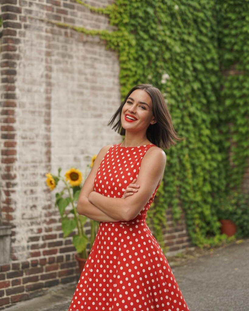 Bold red dress with large white polka dots against ivy brick wall - statement style