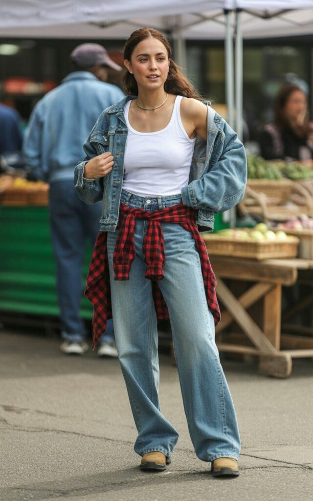 Layered baggy jeans outfit with flannel and denim jacket at outdoor farmers market setting