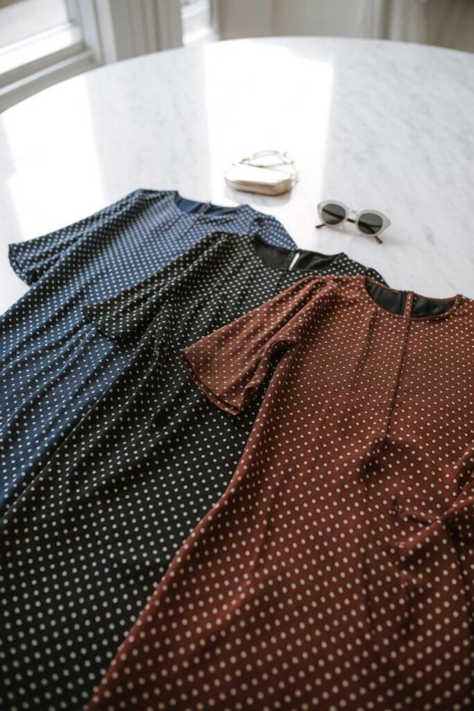 Three polka dot dresses in navy, black, and burgundy on marble surface - style variety