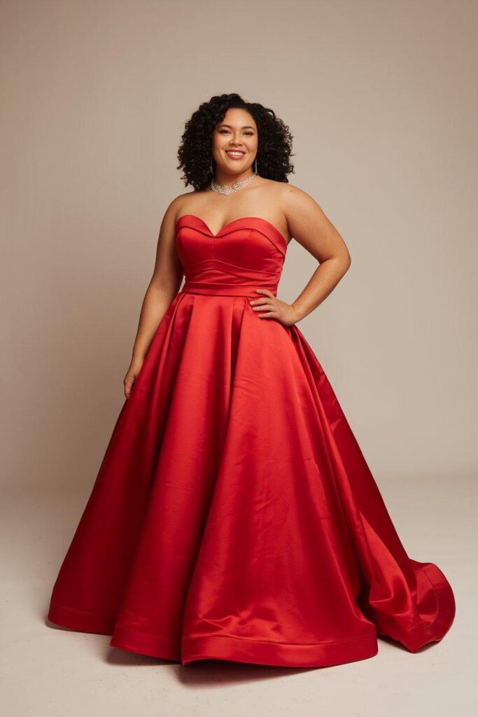 Plus size woman in red strapless sweetheart prom dress smiling confidently