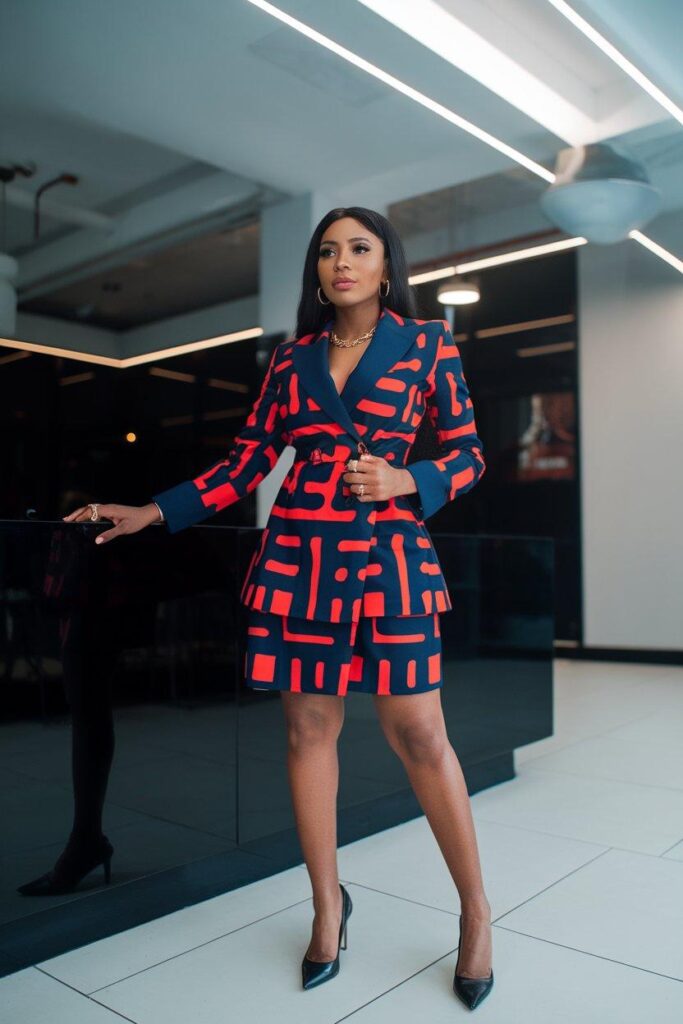 African woman in bold Ankara blazer dress standing in modern office lobby