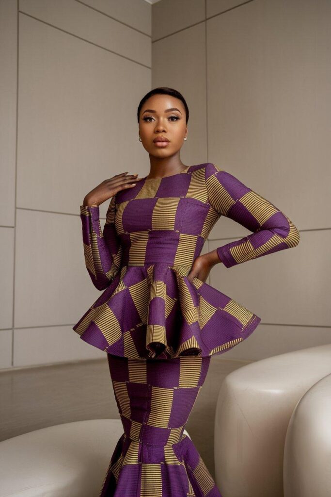 Woman wearing fitted Ankara peplum dress with gold and purple prints