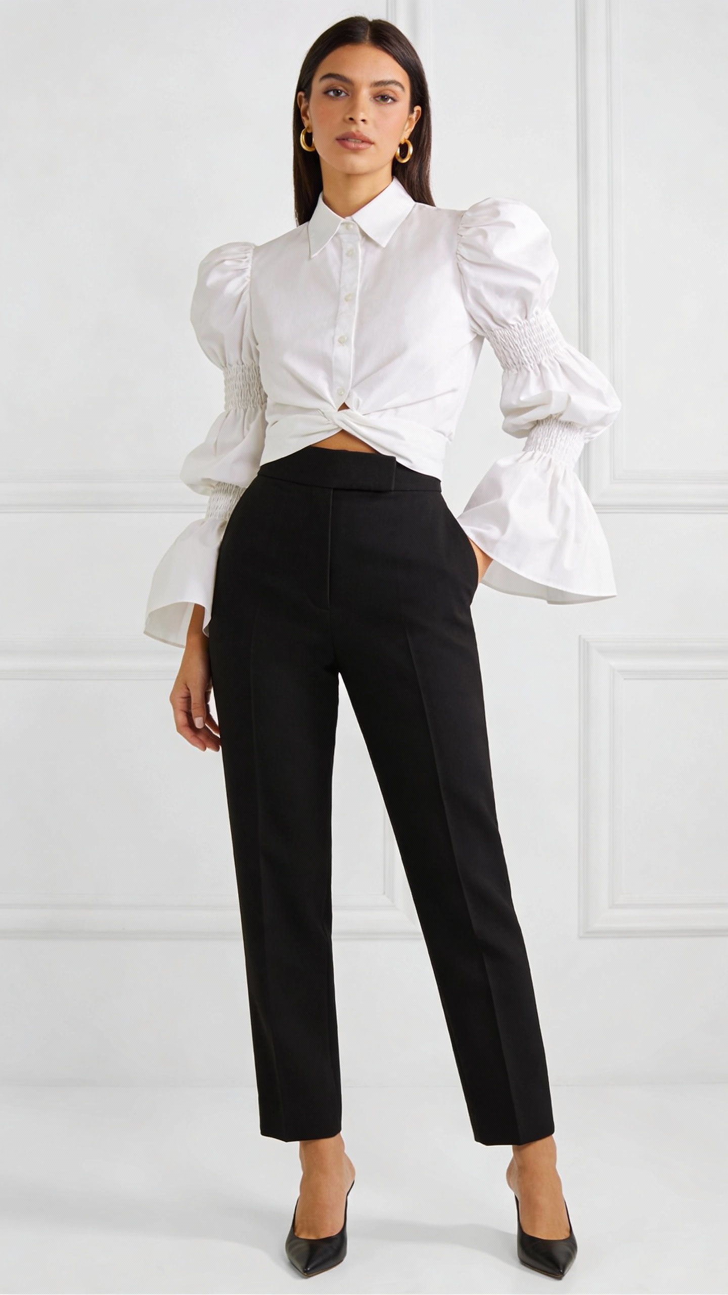A chic, confident woman wearing a crisp white puff-sleeve blouse with delicate smocking details and dramatic yet elegant sleeves, paired with high-waisted tailored black trousers for a sleek contrast. The blouse is French-tucked to accentuate her waist, and her pointed-toe mules add a polished finish. Minimalist gold hoop earrings provide subtle sophistication. The setting is a bright, modern studio with soft lighting, capturing her poised stance and the effortless volume of the sleeves. The image exudes contemporary elegance and confidence, as if she effortlessly commands attention with this balanced, trendy ensemble.